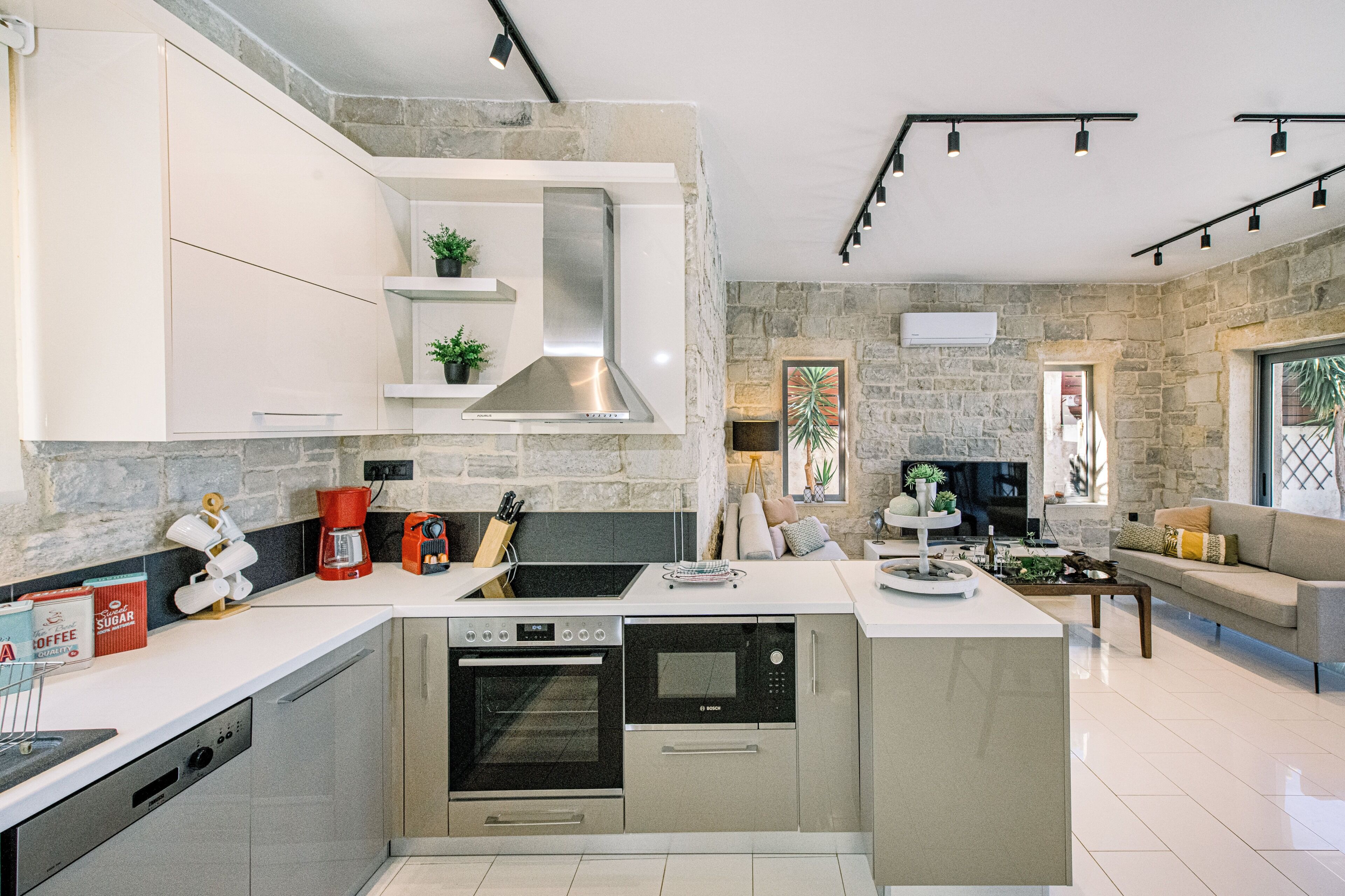 Una cocina moderna con electrodomésticos integrados, una isla central y un fondo de pared de piedra.