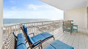 Varanda com móveis de vime e vista para a praia.