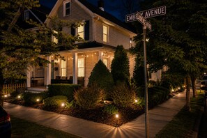 Une maison située sur l’avenue Embelliance, dotée d’un porche, de guirlandes lumineuses et d’un jardin bien entretenu.
