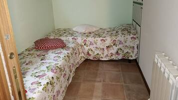 Quarto pequeno com duas camas, um radiador e uma obra de arte pendurada na parede.