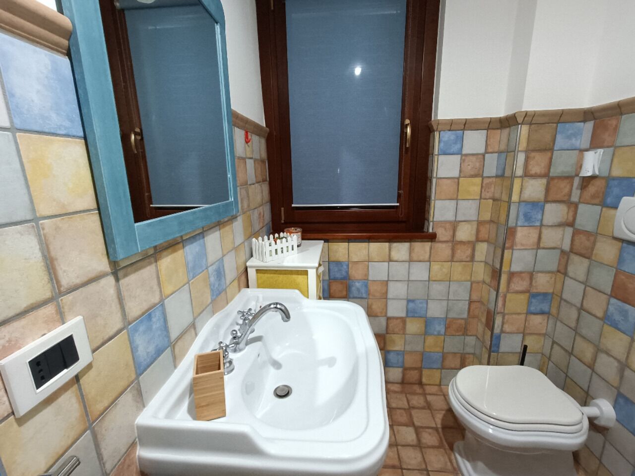 A bathroom with a white sink, a mirror, a toilet, and a window.