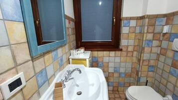 A bathroom with a white sink, a mirror, a toilet, and a window.