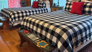Ein Schlafzimmer einer Holzhütte mit zwei Betten, einer Bank und einem Deckenventilator.