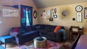 Uma sala de estar aconchegante com um sofá de cor escura, uma mesinha lateral e um tapete colorido.