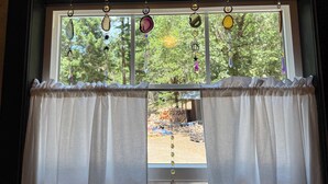 Janela com vista para um jardim e um sonho apanhador pendurado.