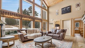 Un salón amplio con ventanas grandes, una chimenea y vistas al exterior.