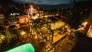 A rooftop pool area with lounge chairs and a small pool, surrounded by palm trees and a wooden deck. - Pousada Cacau Praia do Rosa (Imbituba)