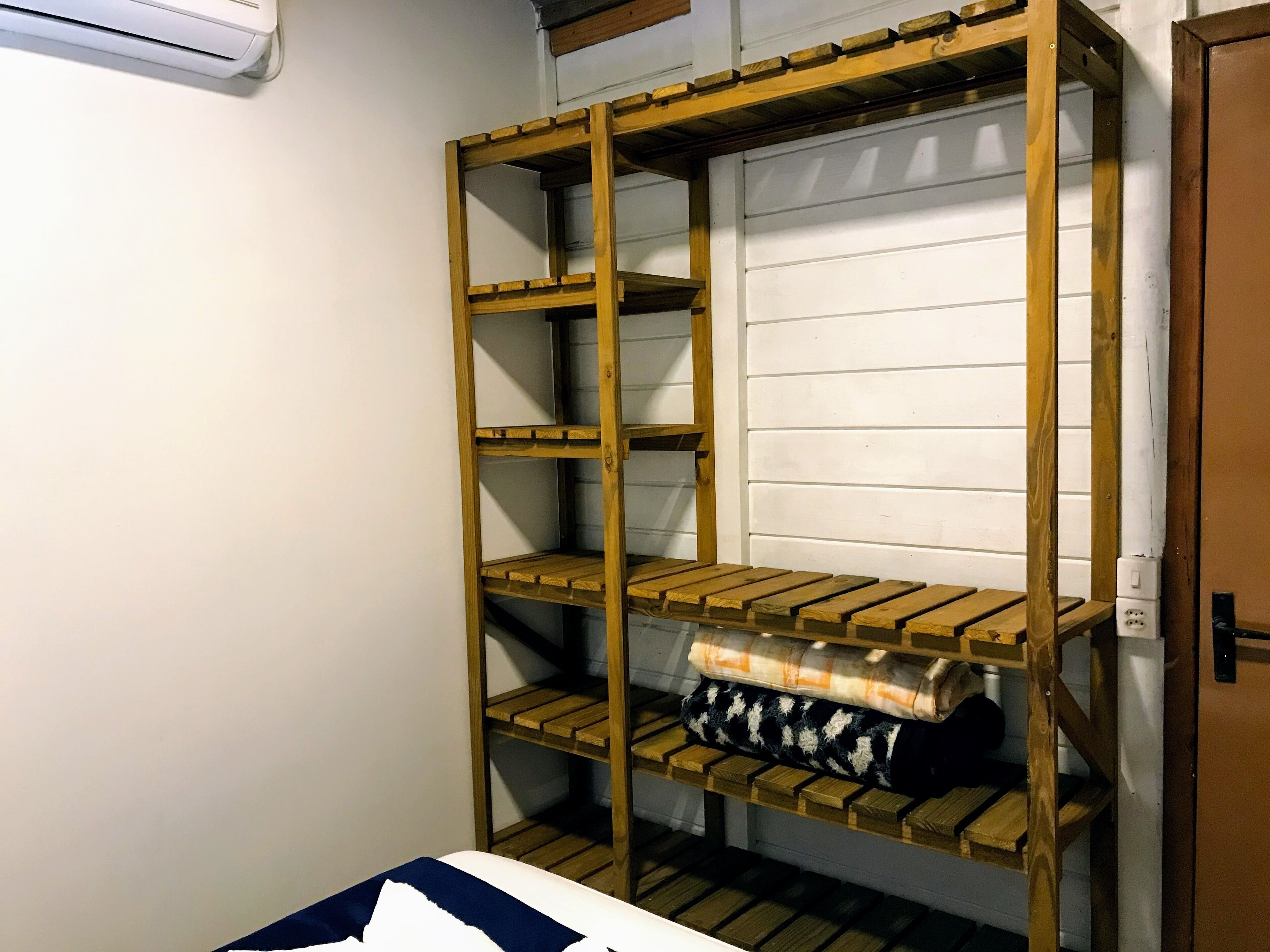 Una cama litera con estantes de madera, una pared blanca y una puerta.