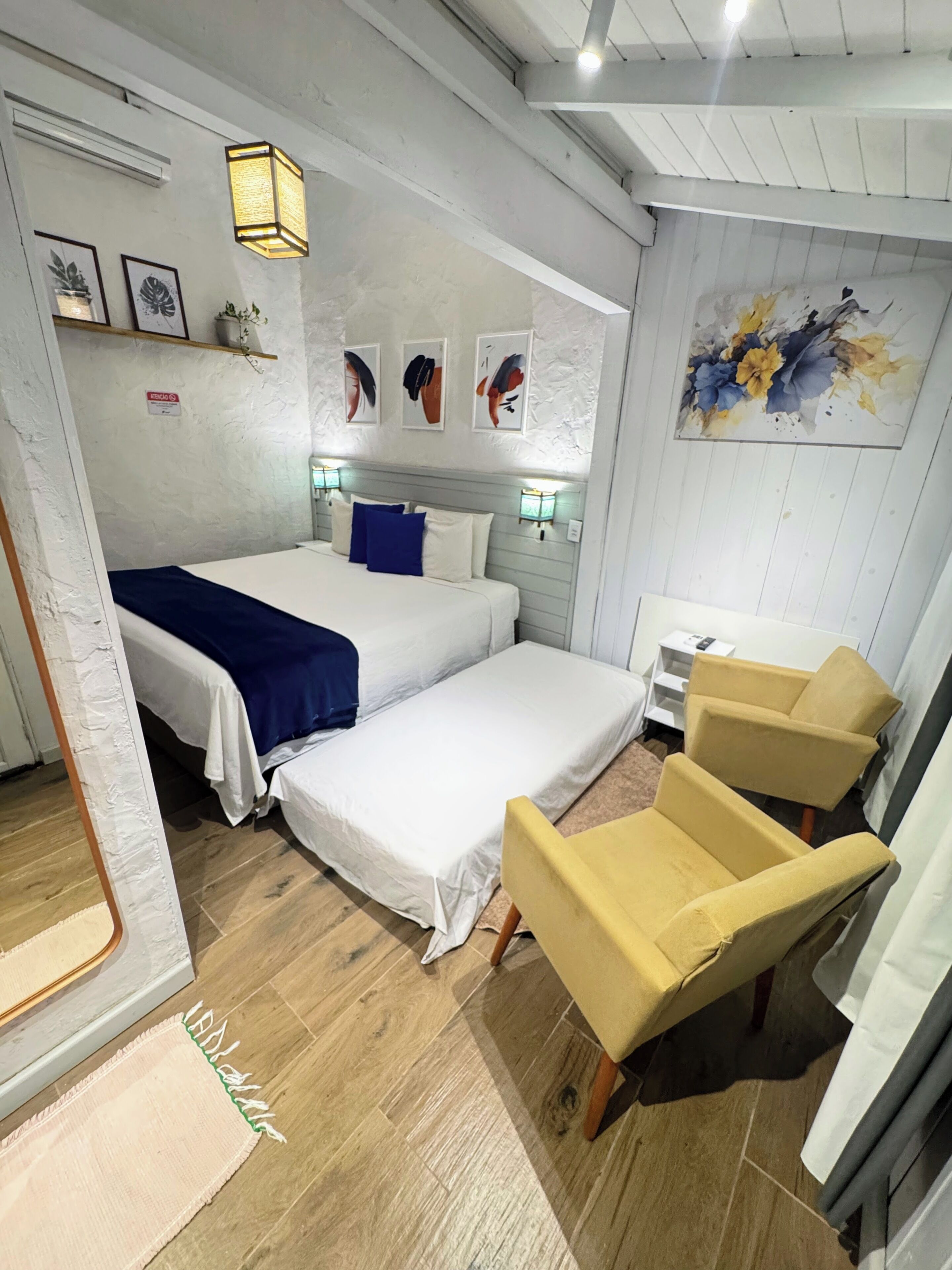 Habitación de hotel con dos camas, un sofá, una silla, un cuadro y un ventilador de techo.