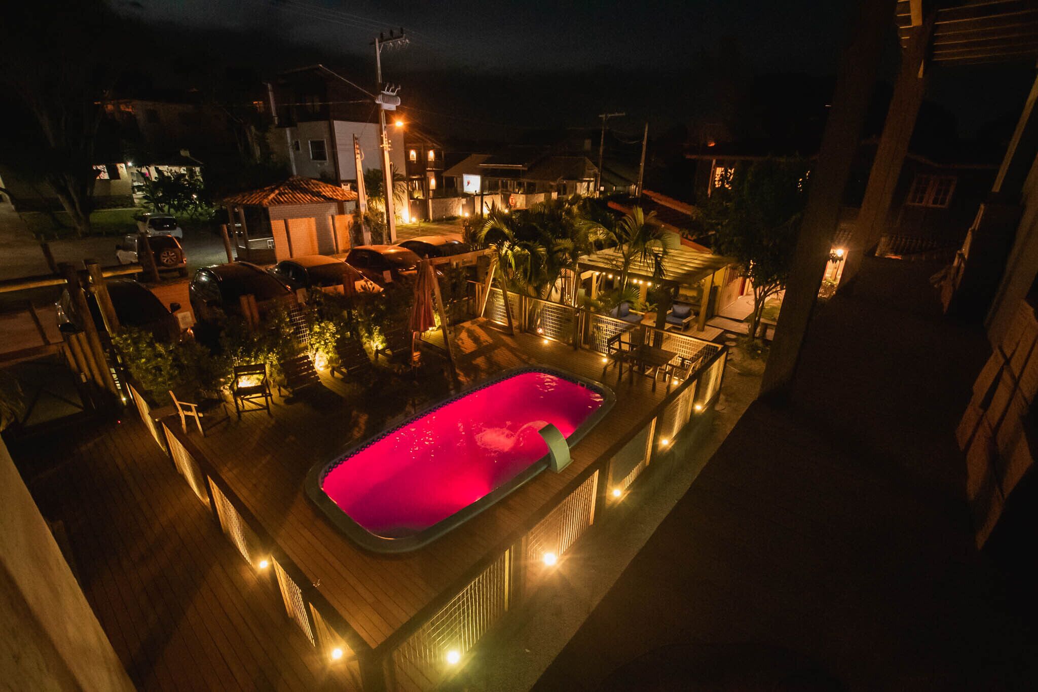 Un área de piscina en la azotea con piscina, sillas de descanso y terraza de madera.