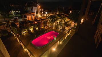 Un área de piscina en la azotea con piscina, sillas de descanso y terraza de madera.