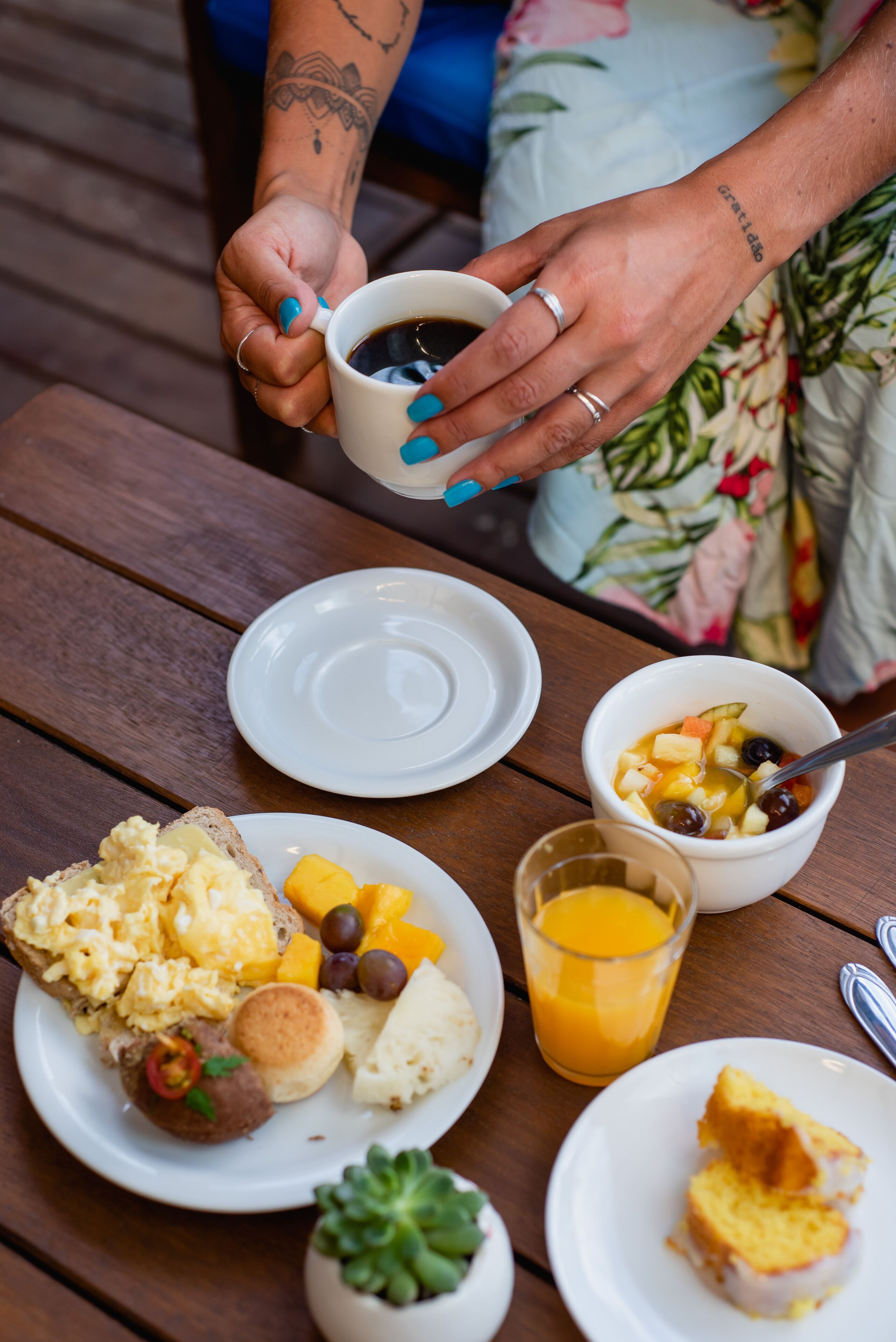 Una mesa de desayuno con platos de comida, una taza de café y un vaso de jugo de naranja.