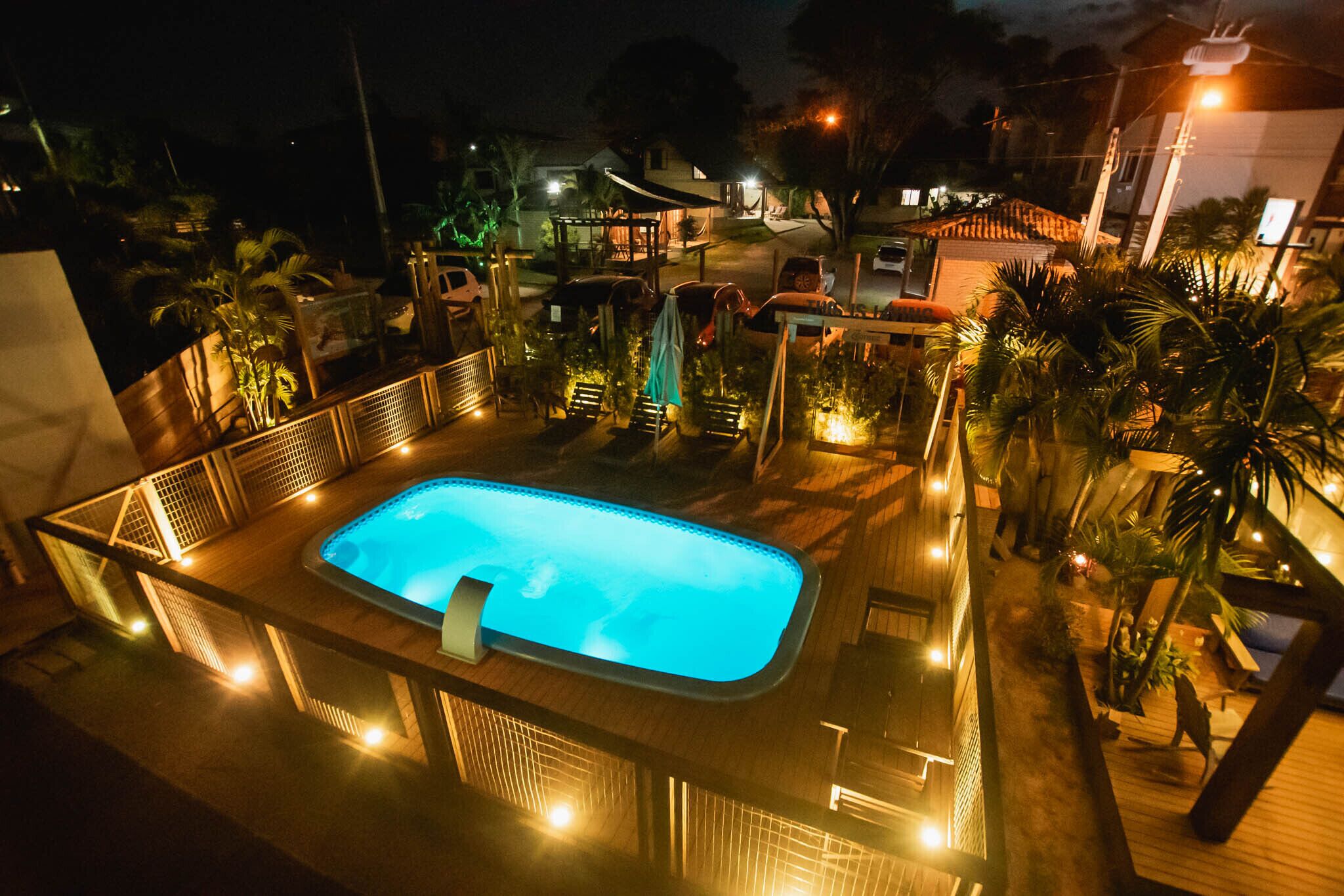 Una piscina en la azotea con terraza de madera y palmeras alrededor.