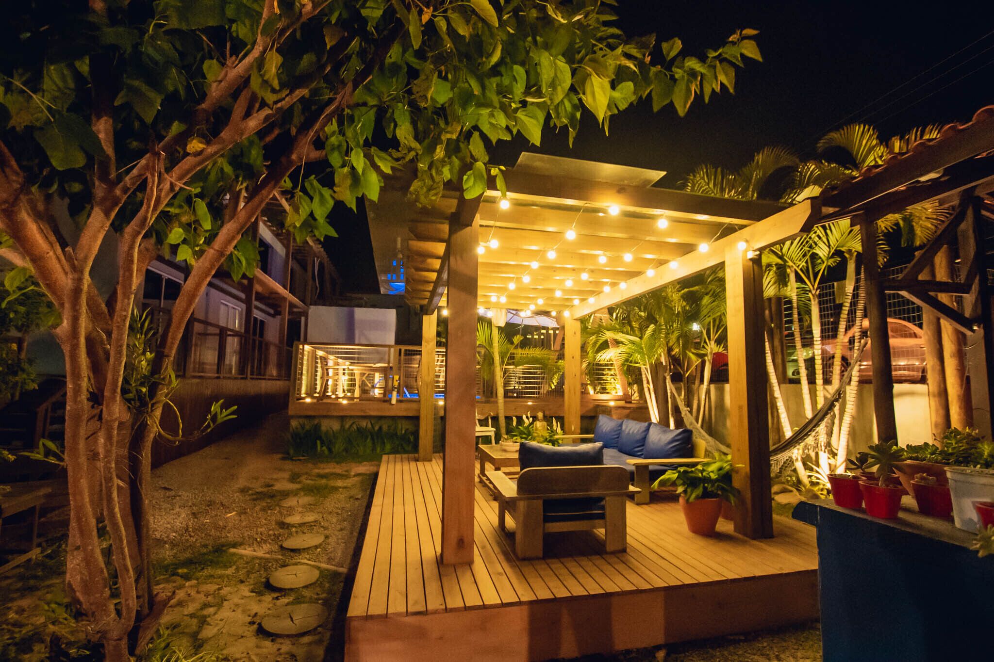A wooden deck with a hammock, seating area, and potted plants.