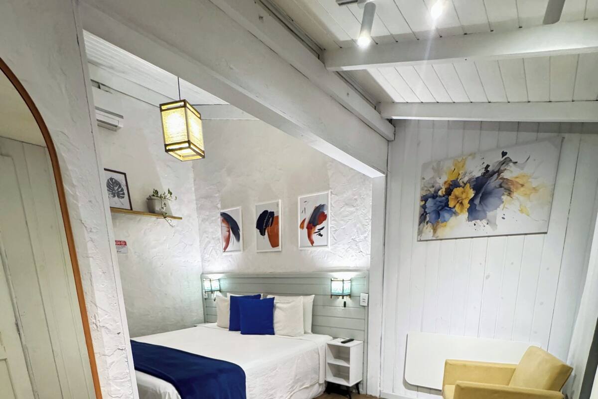 A bedroom with a bed, bedside tables, a chair, a round rug, and artwork on the walls.