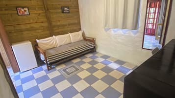 Una habitación con piso a cuadros, un sofá, una mesita y una ventana con cortinas.