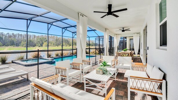 A covered outdoor area with a pool, white furniture, and ceiling fans. - EV_3009 - 9BR / 5BA Storey Lake Villa near to Disney, Private Pool & Games Room (Kissimmee)