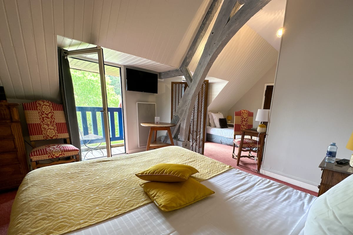 Une chambre avec un grand lit, un bureau, une chaise et un balcon.