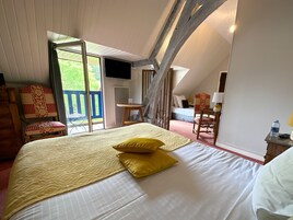 Un dormitorio con una cama grande, un escritorio, una silla y un balcón.