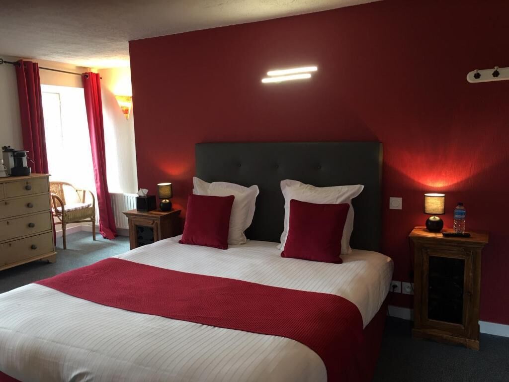 Et hotelværelse med en stor seng, røde vægge og to sengeborde med lamper.