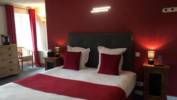 Quarto de hotel com uma cama grande, paredes vermelhas e duas mesas de cabeceira com abajures.