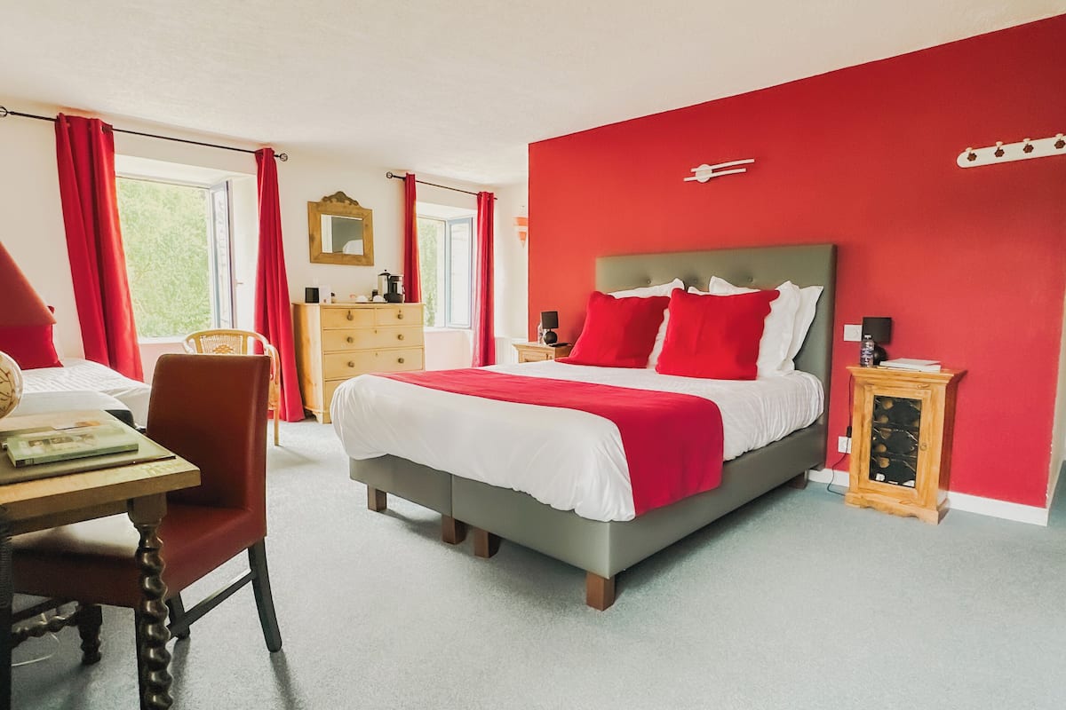 Une chambre à coucher avec un lit, une commode, une chaise et une table de chevet.