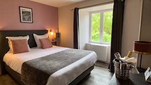 Un lit bien fait, avec des oreillers, une lampe de chevet et une fenêtre avec des rideaux.