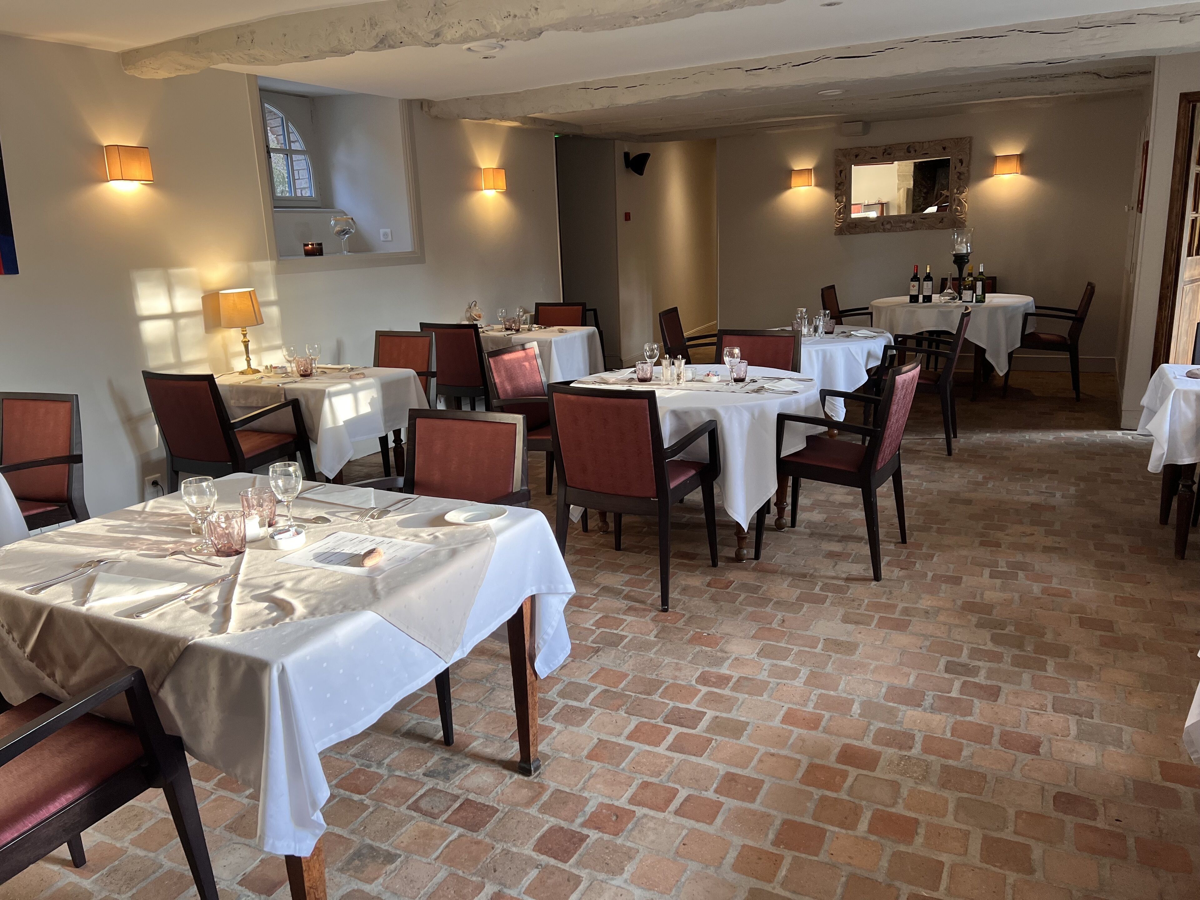A restaurant with multiple tables and chairs, each set with cutlery and glasses.