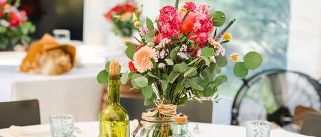 Ein gedeckter Tisch mit klarem Glasgeschirr, einer floralen Tischdekoration und dekorativen Elementen wie Eukalyptusblättern und Holz-Untersetzern.