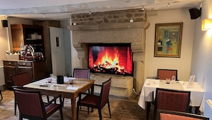 Un coin repas agrémenté d’une cheminée en pierre, de meubles en bois et d’une table dressée pour deux personnes.