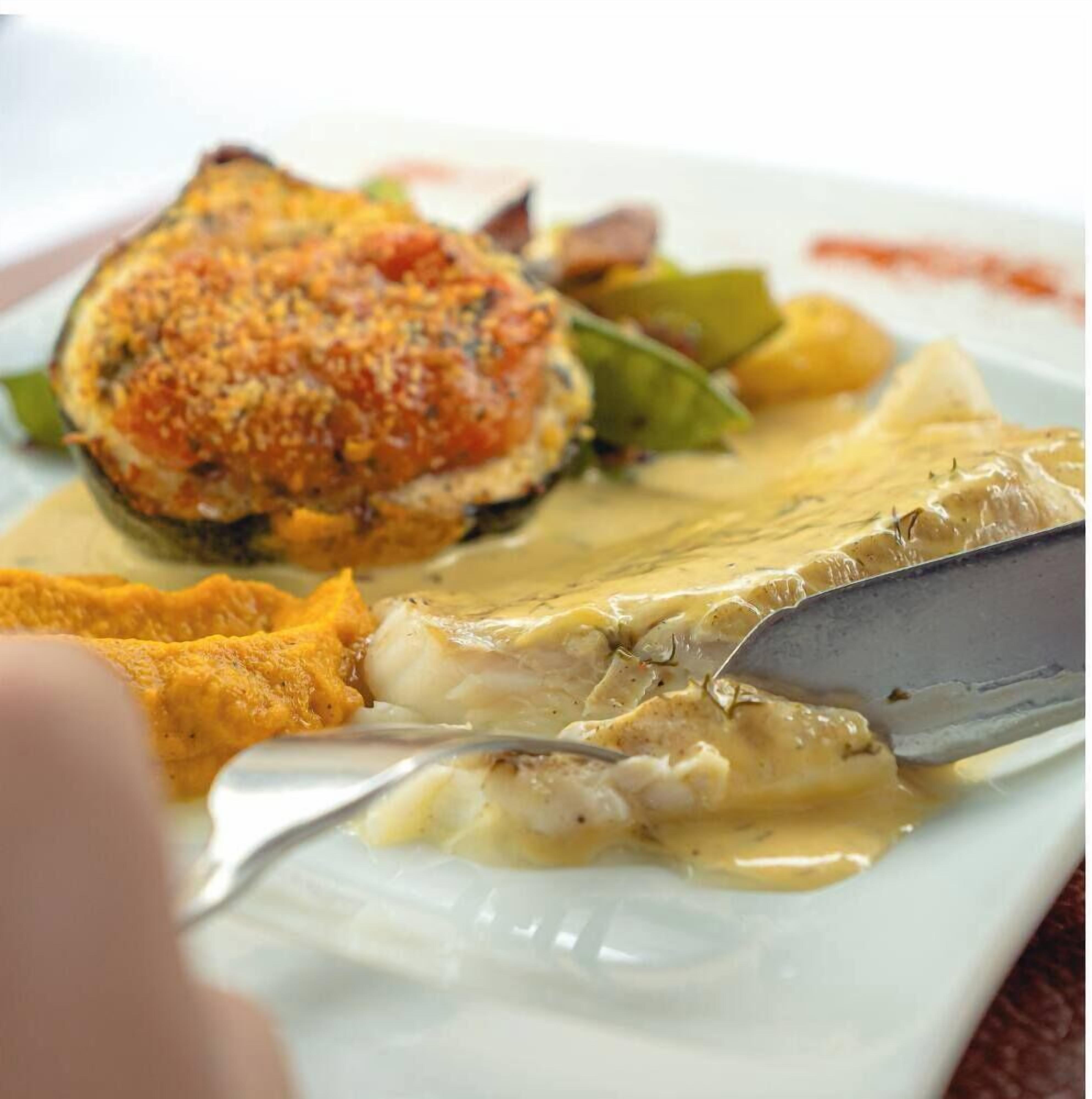 A plate with a piece of fish, a breaded item, and some vegetables.