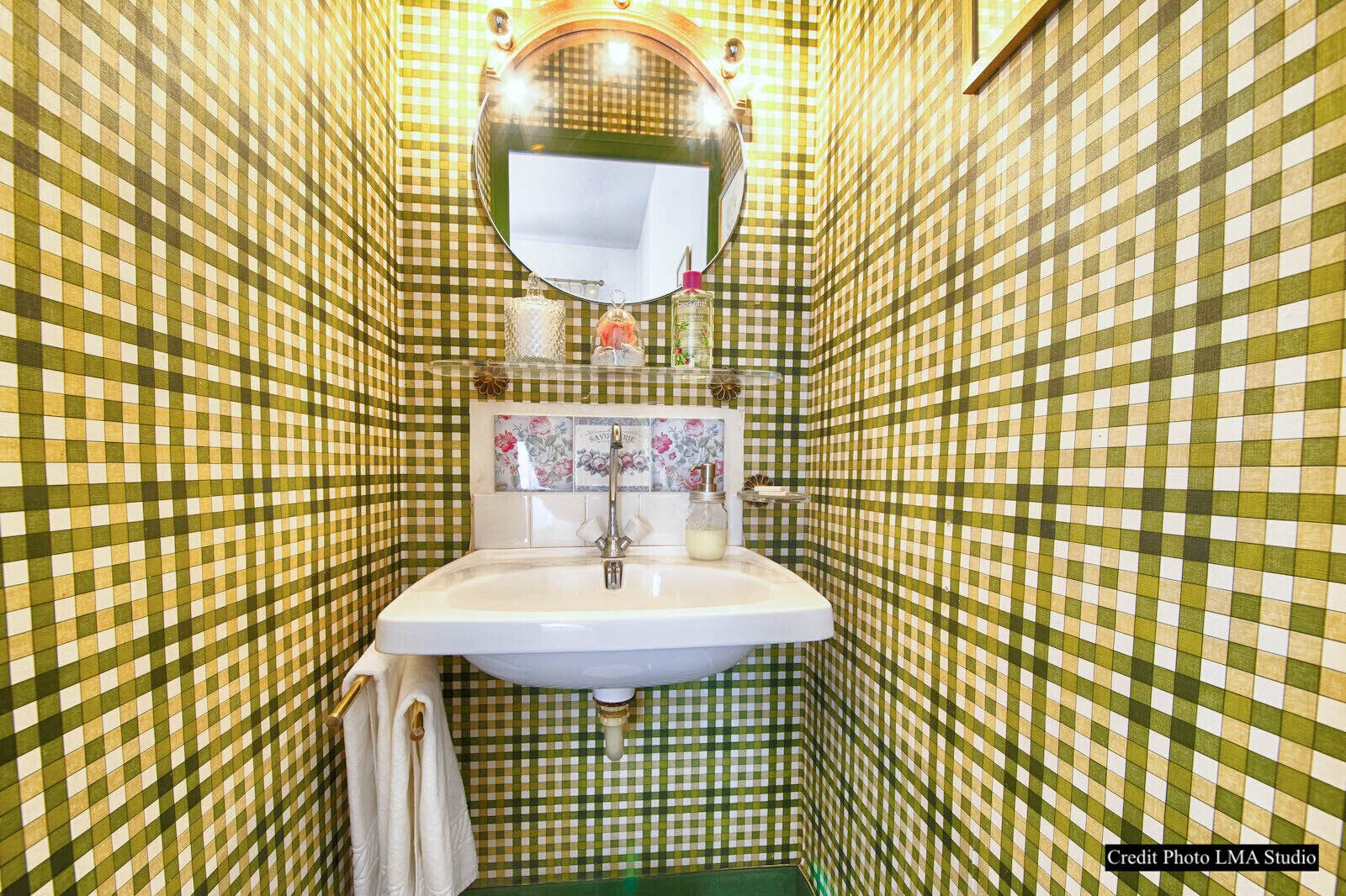 Un baño con suelo de baldosas a cuadros, un lavabo blanco, un espejo y un perchero para toallas.