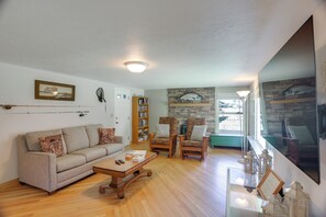 A living room with a sofa, armchairs, a coffee table, a bookshelf, and a stone wall with fish artwork. - Dolores Ranch Cabin w/ Hot Tub & 1-Acre Yard! (Dolores)