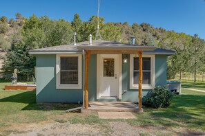 A small, single-story house with a front porch, a chimney, and a satellite dish. - Dolores Ranch Cabin w/ Hot Tub & 1-Acre Yard! (Dolores)