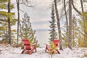 Dos sillas Adirondack rojas mirando hacia un lago con árboles al fondo.