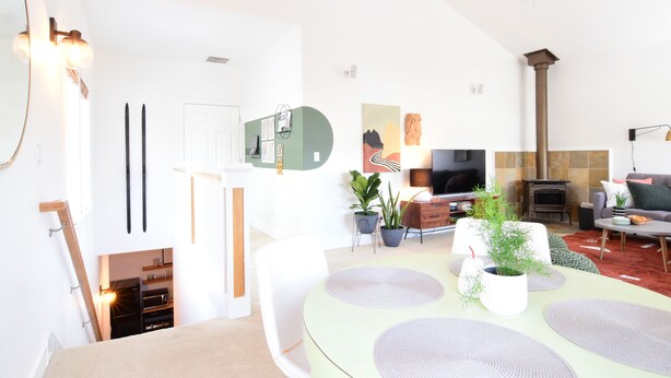 A modern living room with a dining area, a fireplace, and a TV.