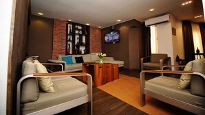A modern living room with a brick accent wall, a flat-screen TV, and a sofa set. - Villa Hotel Tbilisi (თბილისი)
