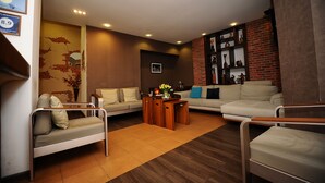 A modern living room with a sofa, a small table, and a brick accent wall. - Villa Hotel Tbilisi (თბილისი)