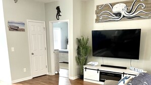 En stue med en stor sofa, et sofabord, et fladskærms-tv og en plante.