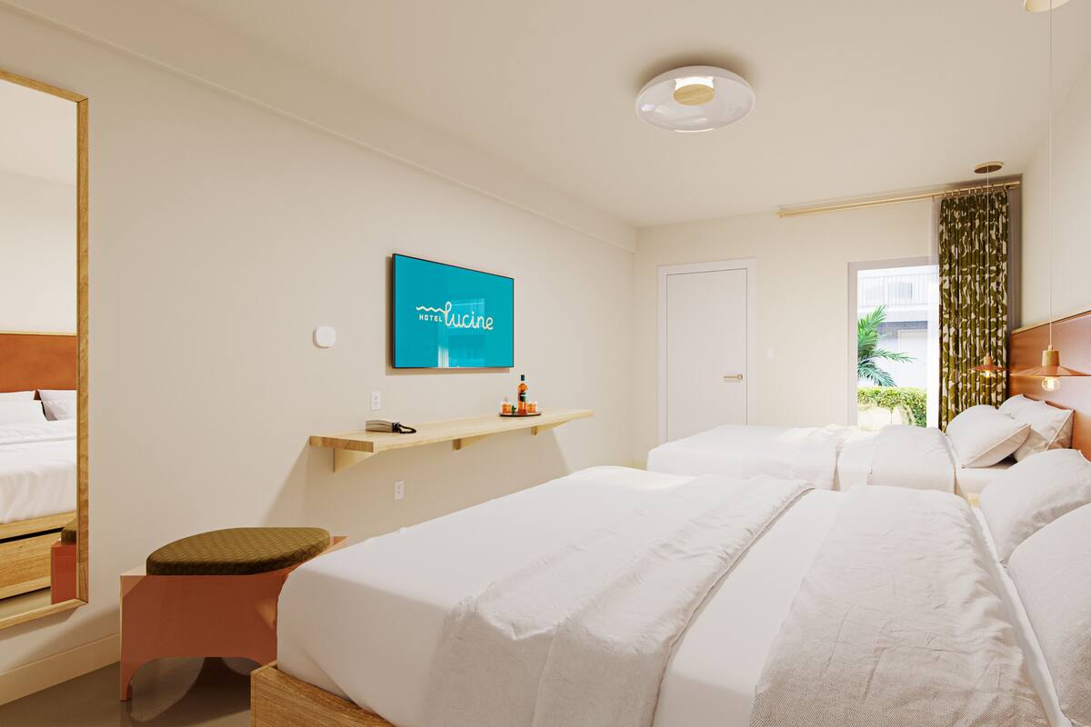 A hotel room with a large bed, a bedside table, a mirror, a wall-mounted TV, and a window with curtains.