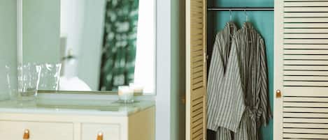 A bathroom with a mirror, a sink, and a towel rack with towels.