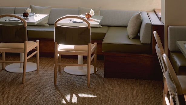 A cozy living room with a large window overlooking the sea, a comfortable seating area, and a dining table with chairs. - Hotel Lucine (Galveston)