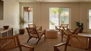 A spacious living room with wicker furniture, large windows, and a view of the outdoors. - Hotel Lucine (Galveston)