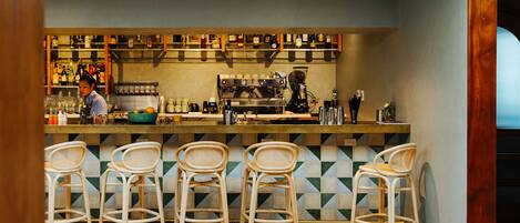 A bar area with a counter, bar stools, and a coffee machine.