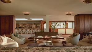 A spacious living area with a sofa set, a coffee table, and a bookshelf. - Hotel Lucine (Galveston)