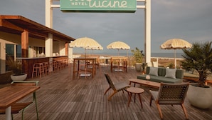 A hotel patio with wooden furniture, umbrellas, and a sign reading "Hotel Lucine." - Hotel Lucine (Galveston)