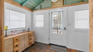 A room with a wooden ceiling, white walls, a wooden dresser, and a door with a glass panel. - Adorable Private Tiny Home  "The Pink House" in Downtown Mt. Dora!! Pet Friendly (Mount Dora)