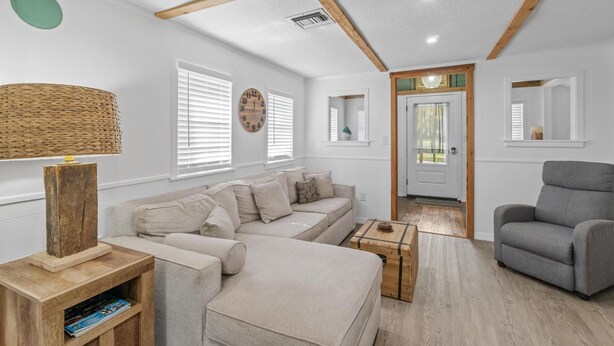 A living room with a sofa, armchair, wooden coffee table, and a lamp. - Adorable Private Tiny Home  "The Pink House" in Downtown Mt. Dora!! Pet Friendly (Mount Dora)