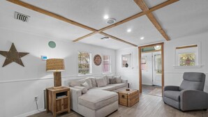 A modern living room with a sectional sofa, a grey armchair, and a wooden coffee table. - Adorable Private Tiny Home  "The Pink House" in Downtown Mt. Dora!! Pet Friendly (Mount Dora)