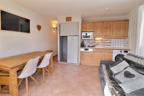 A compact kitchen with wooden cabinets, a built-in microwave, and a washing machine.